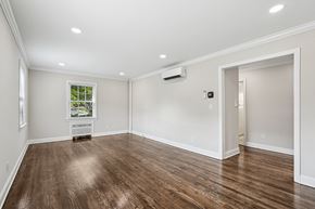 Summit apartment for rent - A room with wood flooring and a window with a view of trees and a white air conditioner on the wall.