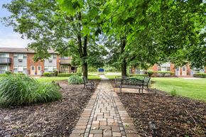 Lafayette apartment for rent - a park with benches and trees in front of an apartment building