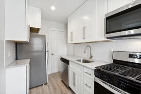 Orange townhouse for rent - an all white kitchen with stainless steel appliances and white cabinets