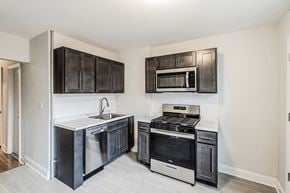 Kearny apartment for rent - an empty kitchen with black cabinets and stainless steel appliances