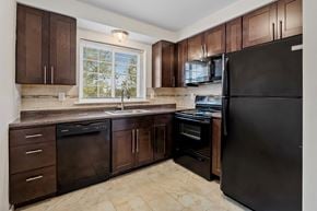 Woodbury apartment for rent - a kitchen with dark wood cabinets and a black refrigerator