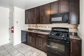 Dover apartment for rent - a kitchen with dark wood cabinets and a stove and a microwave