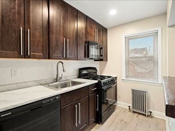 Lodi apartment for rent - A kitchen with dark wood cabinets and black appliances.