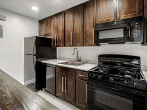 Hasbrouck Heights apartment for rent - A kitchen with black appliances and wooden cabinets.