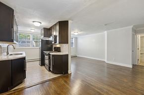 Orange apartment for rent - an empty kitchen and living room with wood flooring and dark cabinets