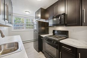 Orange apartment for rent - a kitchen with black cabinets and stainless steel appliances and a sink