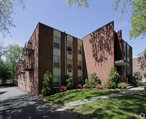 South Orange apartment for rent - exterior view of a brick apartment building with green grass and trees
