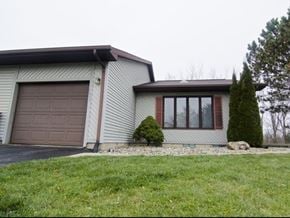 Dewitt triplex for rent - a white house with a brown garage door and a lawn