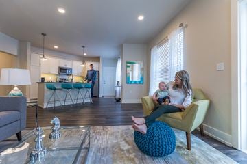 Dewitt apartment for rent - A woman sitting on a yellow chair holding a baby in a modern living room.
