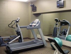 Lansing apartment for rent - a gym with several machines and a tv on the wall