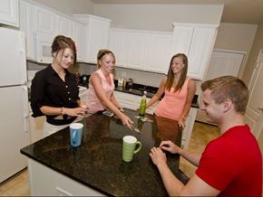 Lansing apartment for rent - a group of people standing around a kitchen counter