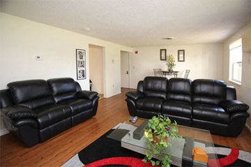 Hyannis apartment for rent - A black leather couch in a living room with a glass coffee table in front of it.