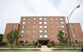 Chicago townhouse for rent - A large red brick building with a black fence in front.