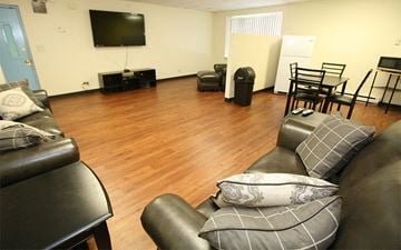 Chicago townhouse for rent - A living room with a black leather couch and a television.