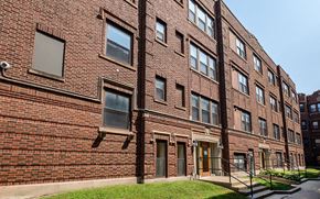 Chicago apartment for rent - A red brick building with a green lawn in front.