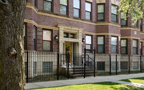 Chicago apartment for rent - A brown building with a black fence and a tree in front.