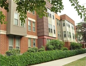 Chicago apartment for rent - A row of red brick apartment buildings with green bushes in front.