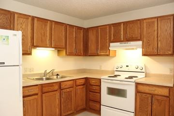 Des Moines triplex for rent - a kitchen with white appliances and wooden cabinets