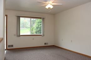Des Moines triplex for rent - an empty living room with a window and a ceiling fan