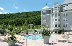 Haverstraw apartment for rent - a swimming pool with chairs and potted plants in front of a building