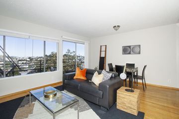 San Francisco apartment for rent - a living room with a couch and a glass coffee table and a dining room table