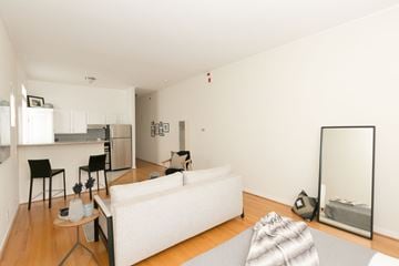 San Francisco apartment for rent - A white couch sits in a living room with a dining table and chairs.