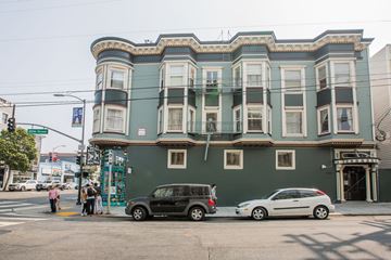 San Francisco apartment for rent - A green building with a black car and white car parked in front.
