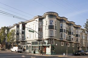 San Francisco apartment for rent - A street view of a building with a green awning and a white van parked in front.