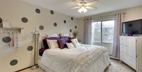 Robbinsdale triplex for rent - A bedroom with a white bed and purple pillows.