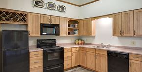 Robbinsdale triplex for rent - A kitchen with wooden cabinets and black appliances.