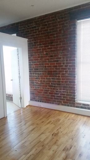 Petersburg apartment for rent - an empty living room with a brick wall and wooden floors
