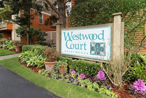 Seattle apartment for rent - A sign for Westwood Court Apartments is surrounded by flowers and plants.