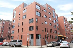 Boston apartment for rent - a tall brick building with cars parked in front of it