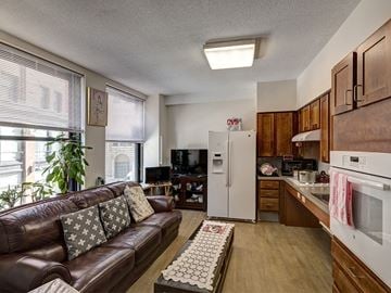 Boston apartment for rent - a living room with a leather couch and a kitchen with a refrigerator