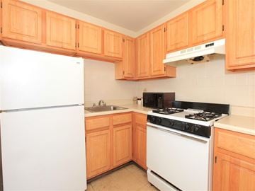 Dorchester apartment for rent - a kitchen with white appliances and wooden cabinets