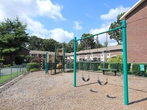 Torrington apartment for rent - a playground with a swing set and monkey bars in front of a building
