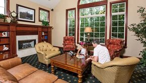 Brookfield apartment for rent - A man and a child are sitting in a living room with a fireplace and a large window.