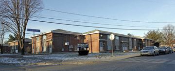 Framingham apartment for rent - A car is parked in front of a brick building with a sign that reads "Pelham".