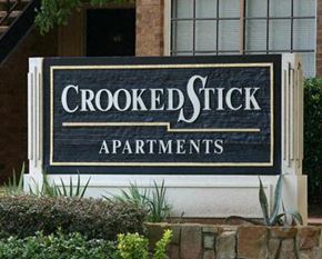 Hurst apartment for rent - A sign for Crooked Stick Apartments is displayed in front of a building.