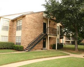 Hurst apartment for rent - A brick house with a black staircase leading to the front door.