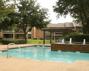Hurst apartment for rent - A pool with a slide and a fountain in front of a building.