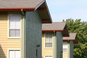 Euless apartment for rent - A building with a yellow and green exterior and a brown roof.