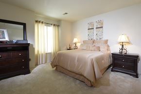 Glen Burnie apartment for rent - A bedroom with a large bed and a dresser with a mirror above it.