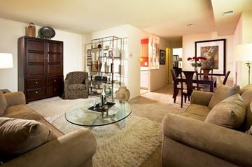 Glen Burnie apartment for rent - A living room with a glass table and brown couches.