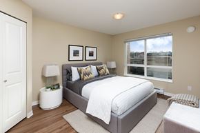 Langley apartment for rent - A bedroom with a large bed and a window overlooking a building.