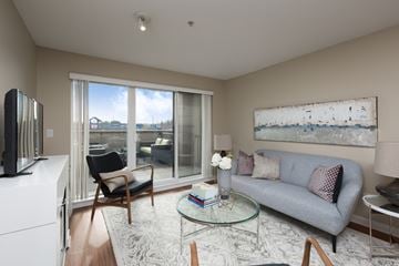 Langley apartment for rent - A living room with a grey couch, a glass coffee table, a television, and a painting on the wall.