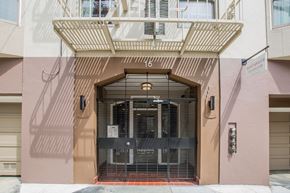 San Francisco apartment for rent - A building with a pink facade has a large gate in front of it.