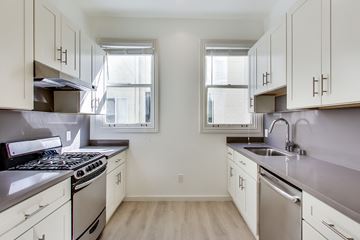 San Francisco apartment for rent - A kitchen with white cabinets and a black stove top oven.