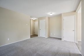 Hillsboro apartment for rent - A spacious room with carpeted floor and three white doors.