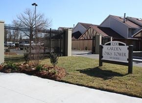 New Orleans apartment for rent - a sign for garden oaks tower in front of a fence
